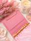 Open pink cash stuffing binder for budgeting with spacious storage, gold binder rings, and elegant feminine desk styling including candles, flowers, and marble accents.